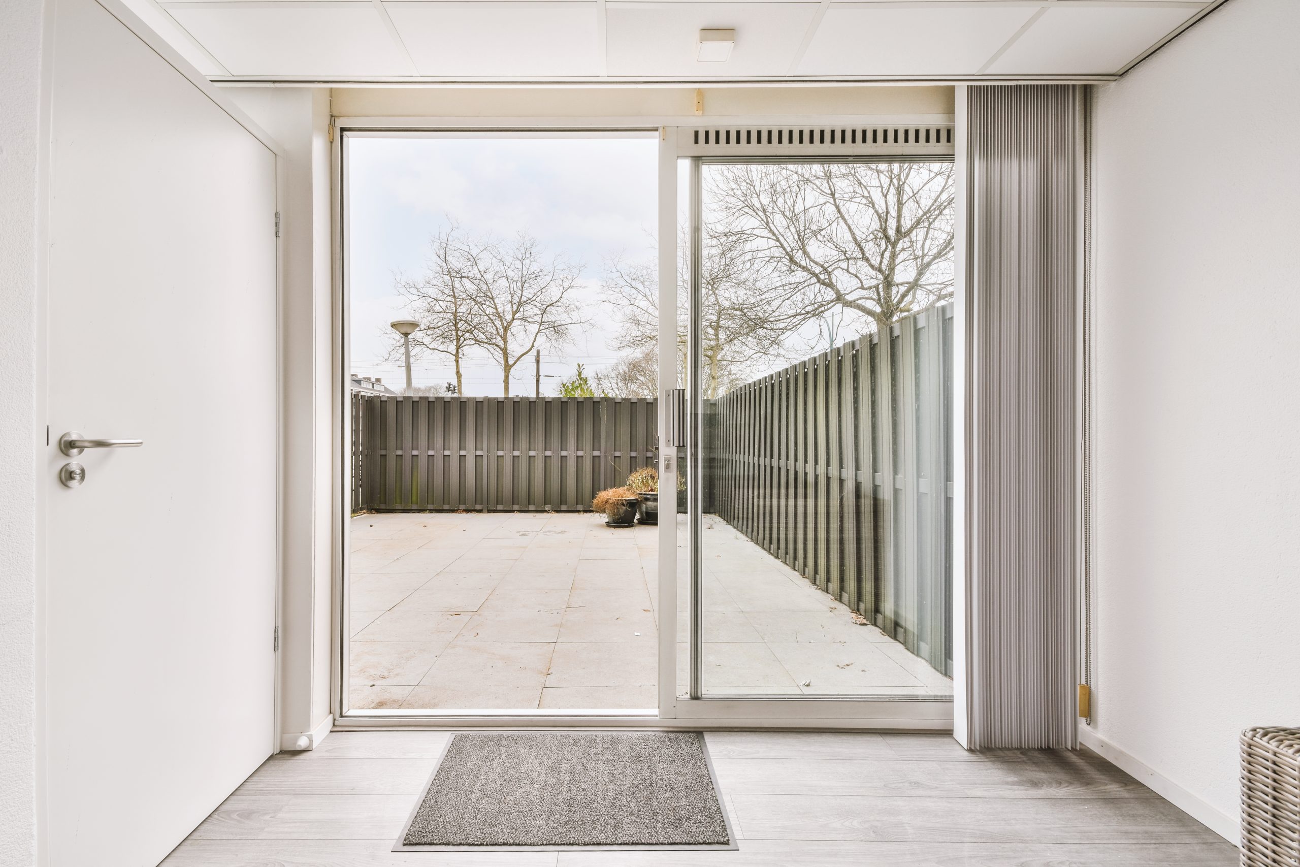 The entrance to bright patio with dark wooden fence in white living room